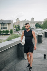Fototapeta premium handsome sportsman walking with yoga mat on roof
