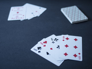 A hand of four six cards against a hand of four aces. Concept for inequality of opportunities or starting positions, social inequality.