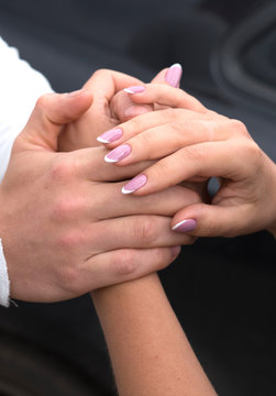 Close-up image of a young couple holding hands.