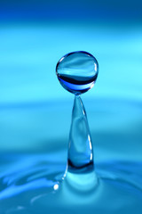 Fototapeta na wymiar Water drop splashing against a blue background
