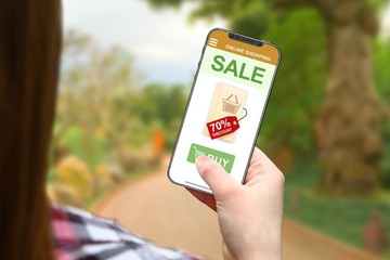 Sale and discount idea, girl with frameless phone on blurred nature background