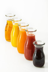unterschiedliche Fruchtsäfte in Glasflaschen vor weissem Hintergrund, Freisteller