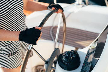 A man holds a yacht's helmet with two hands, wearing mittens in the summer