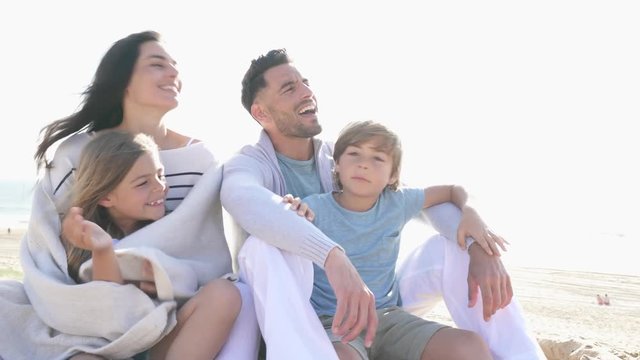 Family sitting on the beach in late afternoon