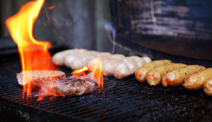 Flame rises around a hamburger on a barbecue
