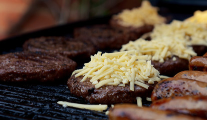 Grated cheese piled on top of a barbecued beefburger