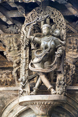 Fototapeta na wymiar Shilabalika, celestial maiden, as a Kapikupite. Monkey, in the bottom left corner, pulling Saree. Chennakeshava temple, Belur, Karnataka. Notice the hairstyle.