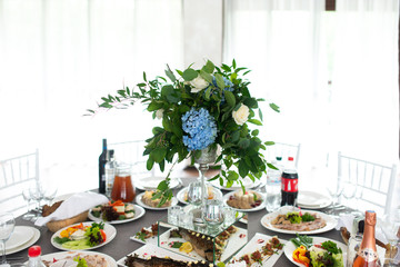 Banquet table is decorated with compositions of hydrangea flowers and greenery