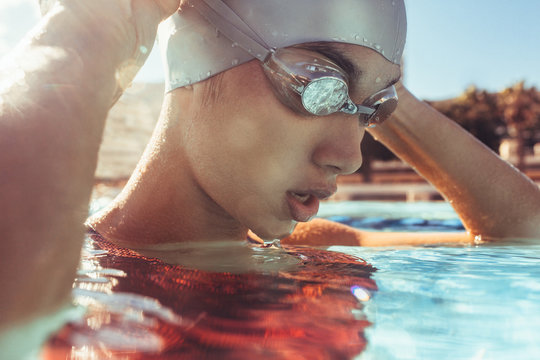 Close up of female swimmer in pool adjusting goggles
