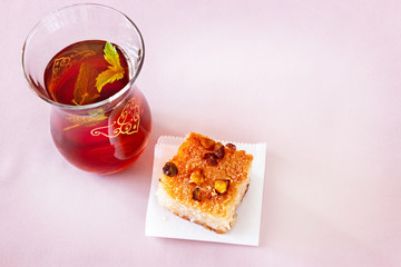 Oriental dessert Basbousa or Namoora. Traditional arabic dessert and glass of mint tea. Delicious homemade semolina cake. Copy spase. Selective focus.