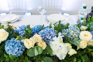 Banquet table is decorated with compositions of hydrangea flowers and greenery