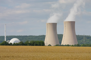 Kernkraftwerk und Stromleitungen in einer Landschaft mit Feldern und Wäldern
