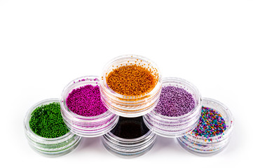 Sequins for nails of different colors in an assortment in boxes on a white background