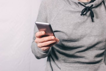 gray smartphone in the hand of a man. gray clothes.
