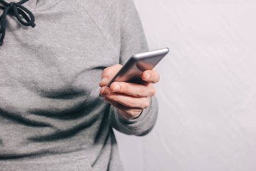 gray smartphone in the hand of a man. gray clothes.