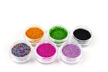 Sequins for nails of different colors in an assortment in boxes on a white background