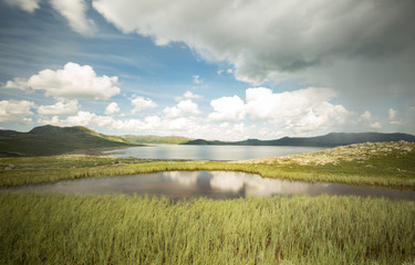 Beautiful norwegian landscape with reflection on the water and a thunderstorm coming from the right side