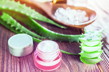 aloe vera gel and rock salt minerals skin cream on wooden background. organic skin care and natural cosmetic for sensitive skin. sliced aloe vera leaf. alternative medicine, spa and skin care concept.