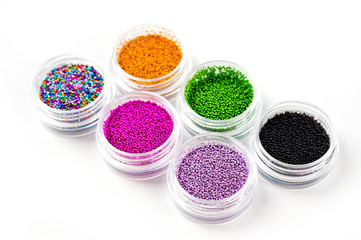 Obraz na płótnie Canvas Sequins for nails of different colors in an assortment in boxes on a white background