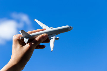 Airplane model in hand on sunny sky. Concepts of travel, transportation