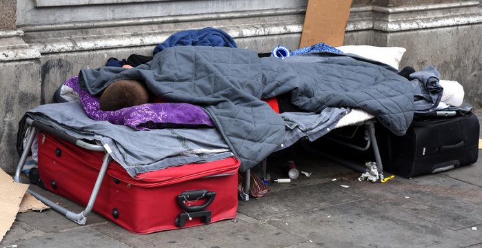Schlafender Obdachloser mit seinem gesamten Hab und Gut unter einer Campingliege