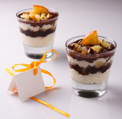 Two glasses of rice pudding with chocolate and candied oranges on the top of it with an empty greeting card beside them; useful for greeting cards, birthday wishes, visit card templates etc.