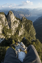 Fototapeta premium Pov sitting on the odge of a cliff in high mountain