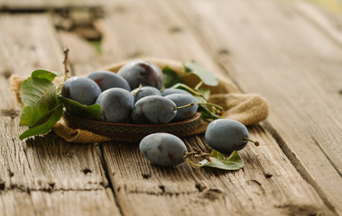 A pile of delicious, ripe, freshly picked plums on a rustic wooden board. Close up.