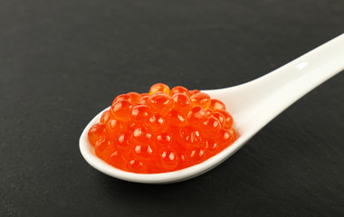 Close up spoon of red salmon caviar on black