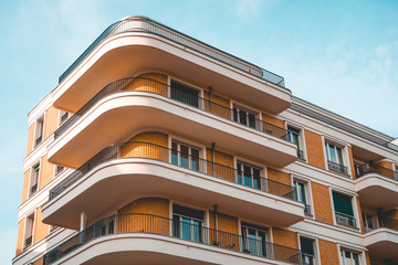 curved corner building with orange facade and white balcony