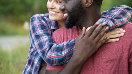 Black man and mixed race woman tenderly hugging, happy people smiling together