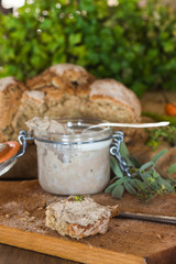 Rustic pâté\pate made from pork liver in a glass jar and a slice of homemade rustic french bread with garlic.
