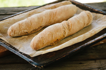 Two tasty, homemade loafs of bread on rustic tray covered with flour on the crust.
