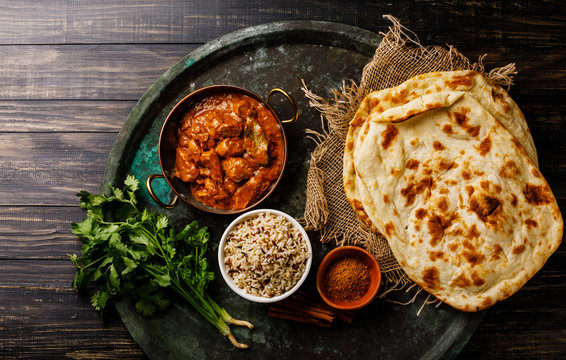 Chicken tikka masala spicy curry meat food with rice and naan bread on dark background