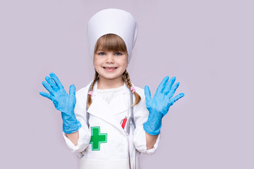 Smiling little girl in medical uniform and blue gloves looking at camera isolated on white