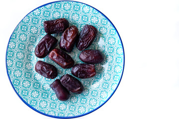 Sweet iranian dates on blue Arabic style plate. Asian and middle east organic product. The source of minerals and vitamins. Raw vegan vegetarian healthy food concept.