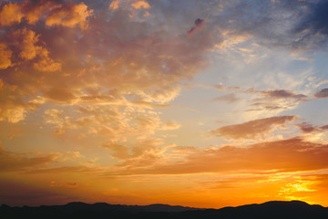 Beautiful sunset with the sun of orange tones behind the mountains and deep blue sky