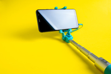 Monopod for selfie with smart phone. Selfie stick with smartphone isolated on yellow background