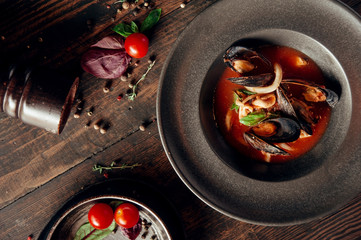 Fototapeta na wymiar mussels in red sauce dish composition at dark wooden background