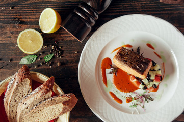 salmon fish grilled steak decorated with bread and lemon at dark wooden background