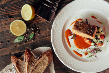 salmon fish grilled steak decorated with bread and lemon at dark wooden background