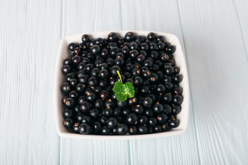 Black currant on wooden table with leaf sprig