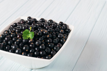 Black currant on wooden table with leaf sprig