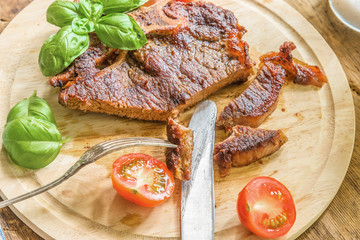 Delicious roast steak with fresh cherry tomatoes and basil leaves on a wooden plate