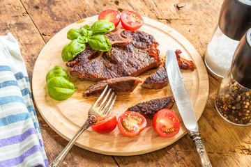 Delicious roast steak with fresh cherry tomatoes and basil leaves on a wooden plate