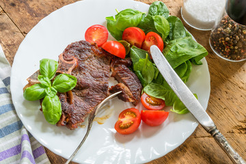 Delicious fried steak with fresh bright salad in a white plate close-up