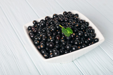 Black currant on wooden table with leaf sprig