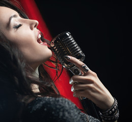 Portrait of beautiful woman singing in microphone