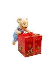 Teddy bear toy is pushing the red gift box tied with decorative braid.Isolated on white