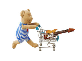 Teddy bear pushing shopping cart with musical instruments. Isolated on white